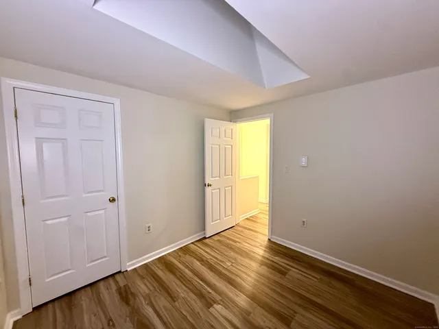 a view of an empty room with wooden floor and closet