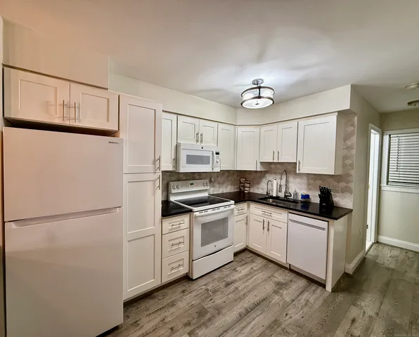 a kitchen with stainless steel appliances granite countertop a refrigerator a stove a sink and white cabinets