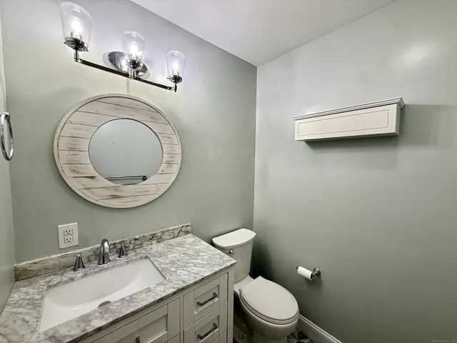 a bathroom with a granite countertop toilet sink mirror and vanity