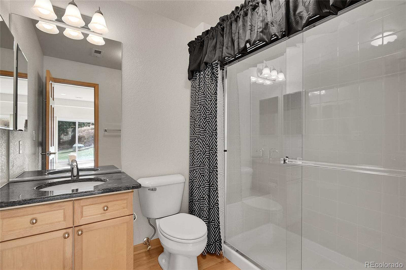 671 Trailside Drive Golden, CO 80401 - Photo 28 of 39 a bathroom with a granite countertop sink toilet a mirror and shower