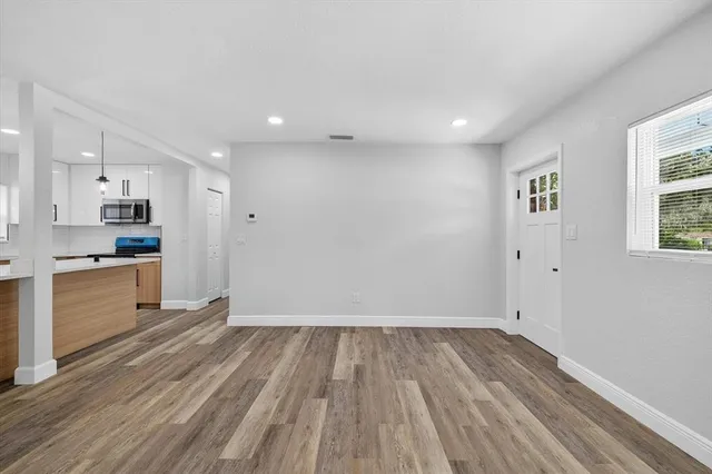 a view of an empty room with wooden floor and a window