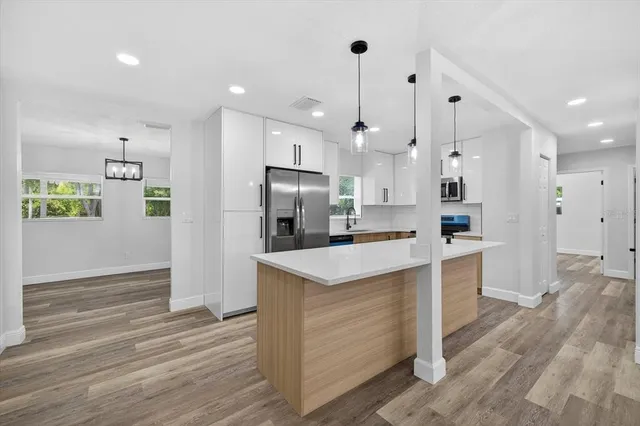 a view of an empty room with wooden floor and windows