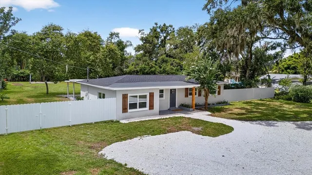 a backyard of a house with potted plants and large tree