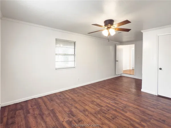 a view of an empty room with wooden floor and a window