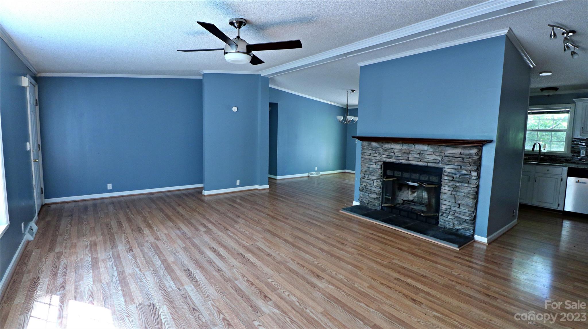 61 Sloan Street Old Fort, NC 28762 - Photo 2 of 38 an empty room with wooden floor a fireplace and window