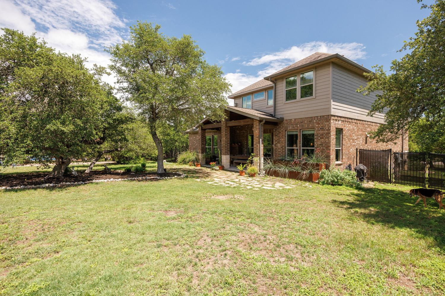 1135 Blue Ridge Drive Dripping Springs, TX 78620 - Photo 28 of 36 A spacious backyard with mature trees and a covered patio, perfect for outdoor enjoyment.