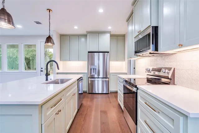 a kitchen with stainless steel appliances granite countertop a sink stove a refrigerator and cabinets with wooden floor