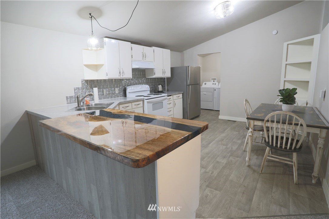 10046 168th Avenue Southwest Rochester, WA 98579 - Photo 8 of 33 a kitchen with stainless steel appliances granite countertop a sink a stove a refrigerator a dining table and chairs