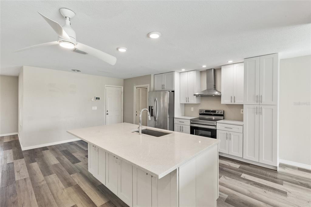 1009 Kings Court Venice, FL 34293 - Photo 3 of 25 a kitchen that has a sink a stove a refrigerator and white cabinets with wooden floor