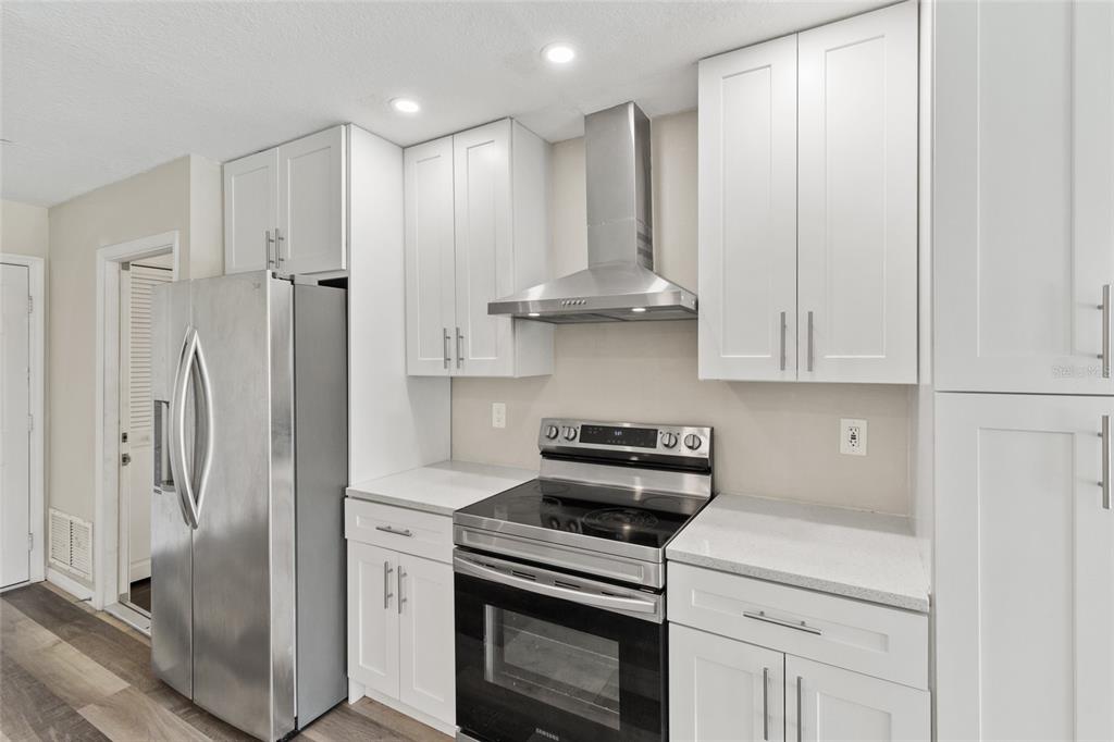 1009 Kings Court Venice, FL 34293 - Photo 4 of 25 a kitchen with stainless steel appliances granite countertop a refrigerator a stove and white cabinets