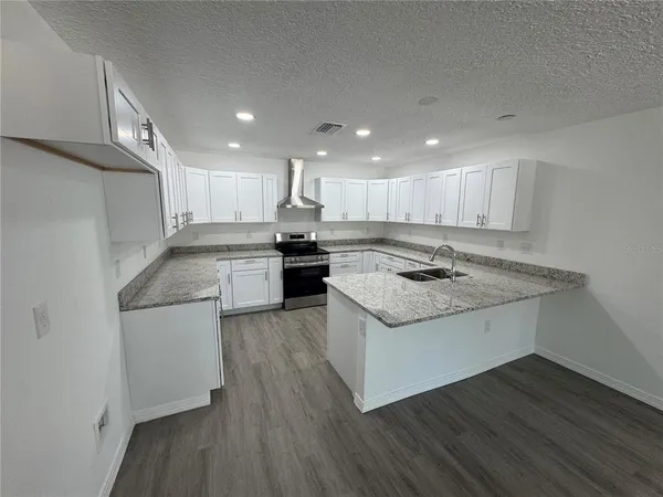 a kitchen with stainless steel appliances granite countertop wooden cabinets and a stove top oven