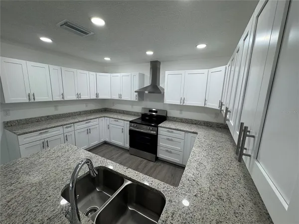 a kitchen with granite countertop stainless steel appliances a stove a sink and a refrigerator