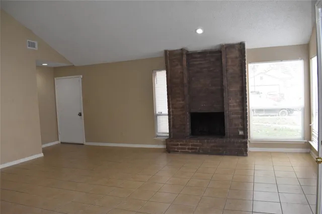 a view of an empty room with a fireplace and a window