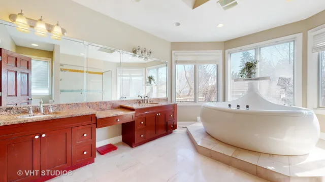 a spacious bathroom with a tub sink double vanity granite and mirror