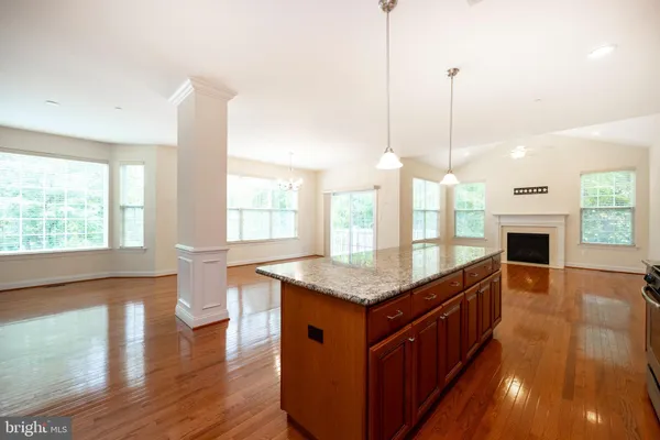 a kitchen with stainless steel appliances granite countertop a stove a sink a center island and a wooden floor