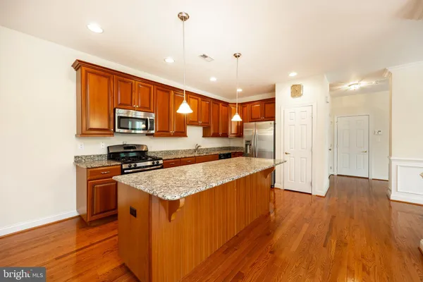 a large kitchen with stainless steel appliances granite countertop a stove a sink dishwasher and a refrigerator with wooden floor