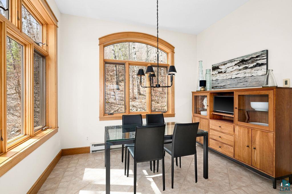 4856 Kingston Street Duluth, MN 55804 - Photo 11 of 88 Dining area featuring extensive wood-trimmed windows with an arched central window, a black iron chandelier, and neutral-toned tile flooring