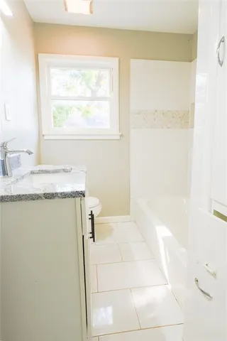 a bathroom with a granite countertop sink and a bathtub