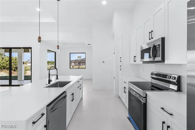 a kitchen with stainless steel appliances a sink a stove a refrigerator a center island and cabinets