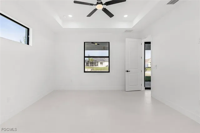 an empty room with windows and ceiling fan
