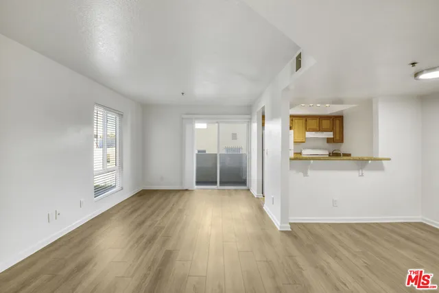 a view of a big room with wooden floor and a kitchen