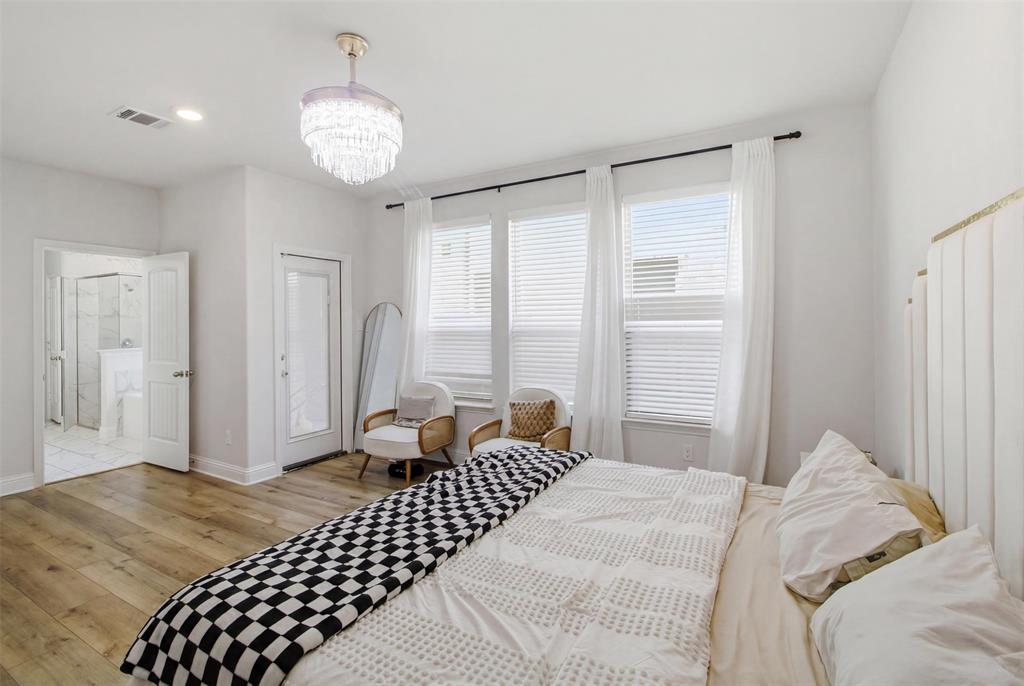 7416 Sequoia Rdg Road Little Elm, TX 76227 - Photo 24 of 37 Bedroom featuring wood-finish flooring, a tiered chandelier, and a white upholstered headboard