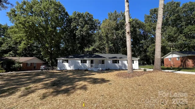 a view of a house with a yard and large trees