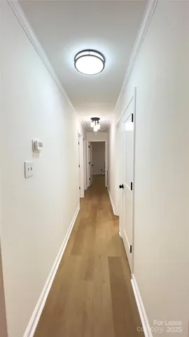 a view of a hallway with wooden floor and a large mirror