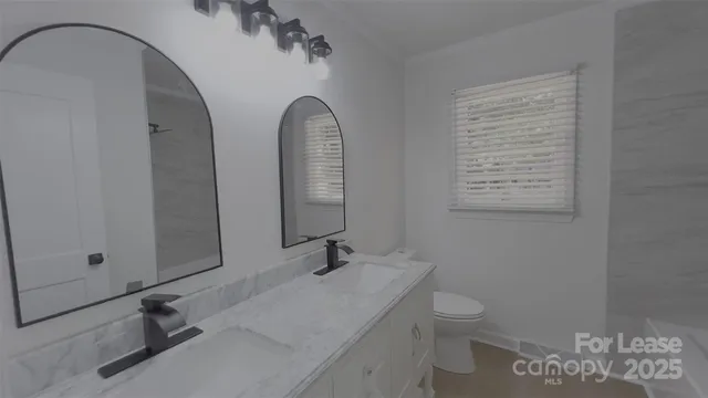 a bathroom with a granite countertop sink a toilet and a mirror