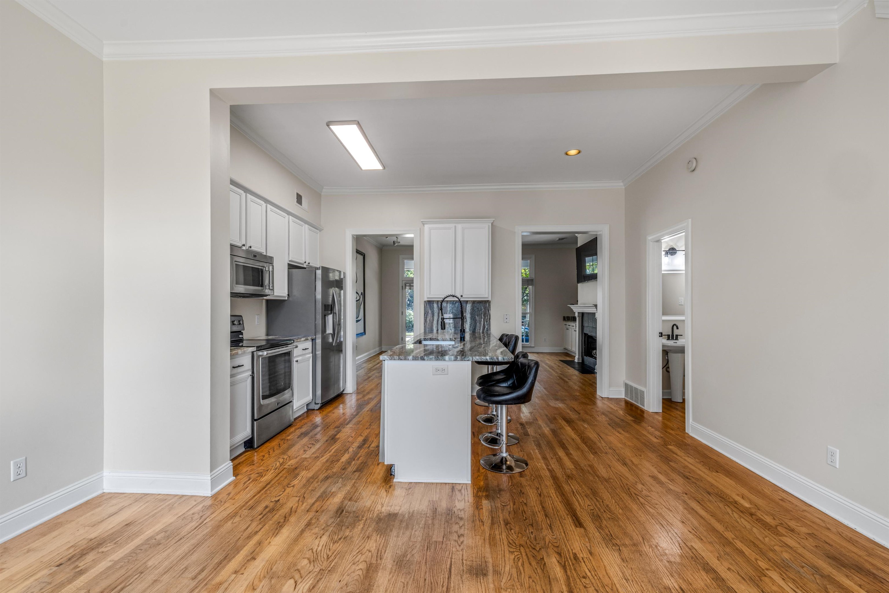 921 Harbor View Drive Memphis, TN 38103 - Photo 18 of 33 Spacious interior with wood-finish flooring, white cabinetry, stainless steel appliances, a kitchen island with seating, and crown molding