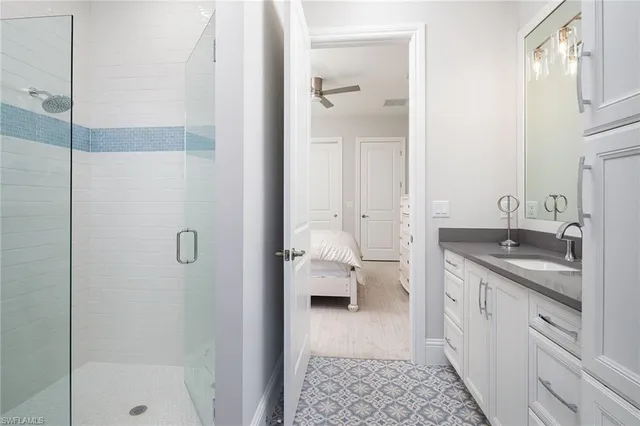 a en suite bathroom with a granite countertop sink a mirror and a shower