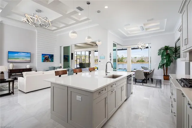 a large white kitchen with a large island in the center and dining table