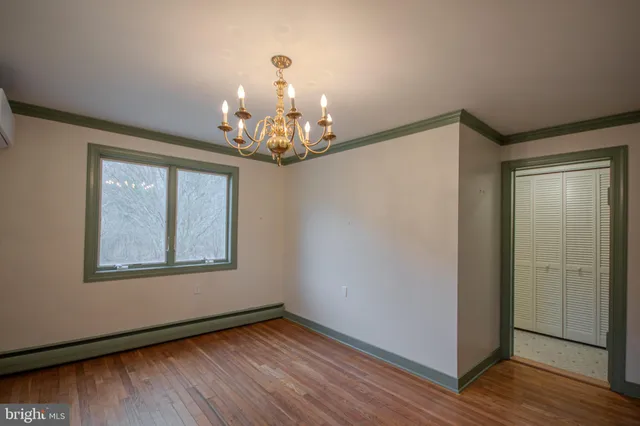 an empty room with wooden floor chandelier and windows