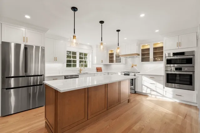 a kitchen with stainless steel appliances granite countertop a refrigerator a sink a stove and a wooden floors