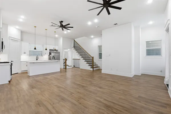 a kitchen with stainless steel appliances granite countertop a sink a stove a refrigerator and island with wooden floor