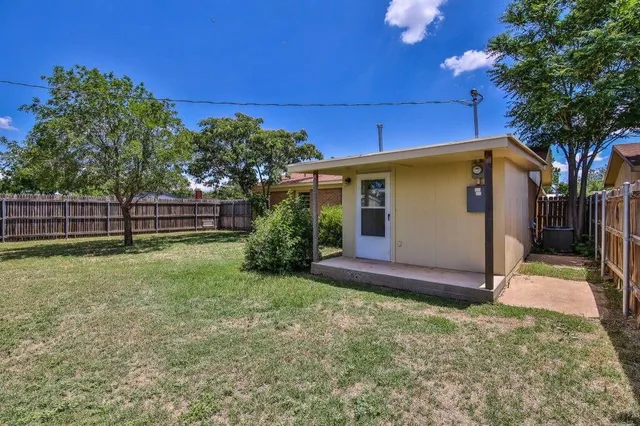 a view of backyard with wooden fence and large trees