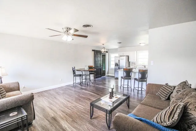 a living room with furniture a rug and a ceiling fan