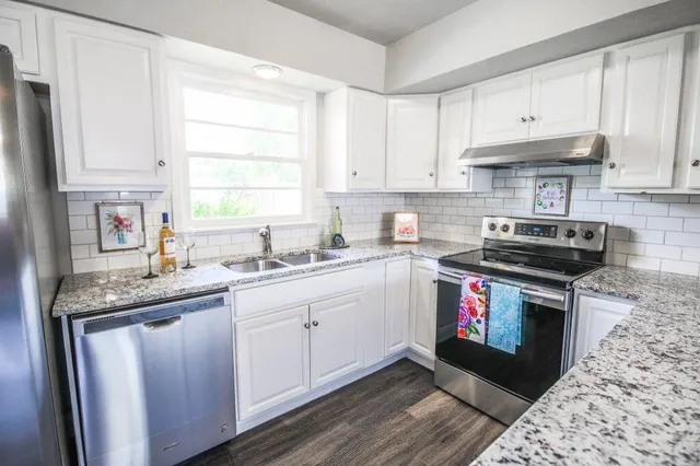 a kitchen with stainless steel appliances granite countertop a stove a sink and a microwave