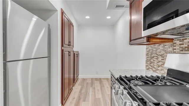 a kitchen with stainless steel appliances granite countertop a refrigerator and a stove top oven