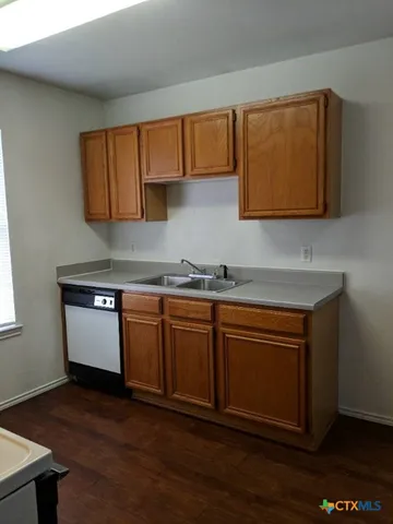a kitchen with granite countertop wooden cabinets a sink and dishwasher