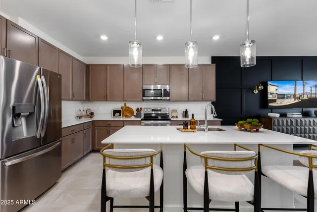 a kitchen with stainless steel appliances granite countertop a sink a stove a refrigerator cabinets and chairs