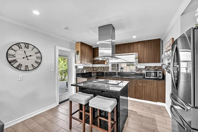 a kitchen with kitchen island granite countertop a refrigerator dining table and chairs