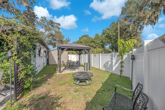 a backyard of a house with table and chairs under an umbrella