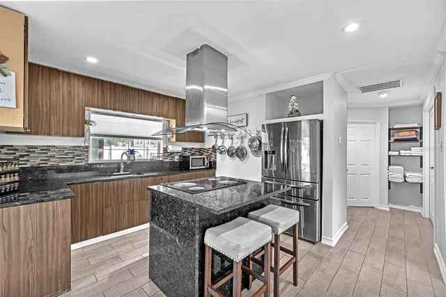 a kitchen with granite countertop kitchen island stainless steel appliances a sink stove and refrigerator