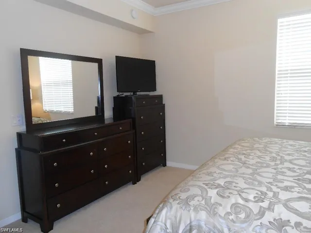 a bedroom with a bed and a flat tv screen on a dresser