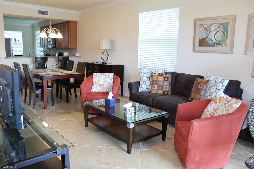 9735 Acqua Court, Unit 611 Naples, FL 34113 - Photo 7 of 30 Living room with light tile patterned floors, ornamental molding, and a chandelier
