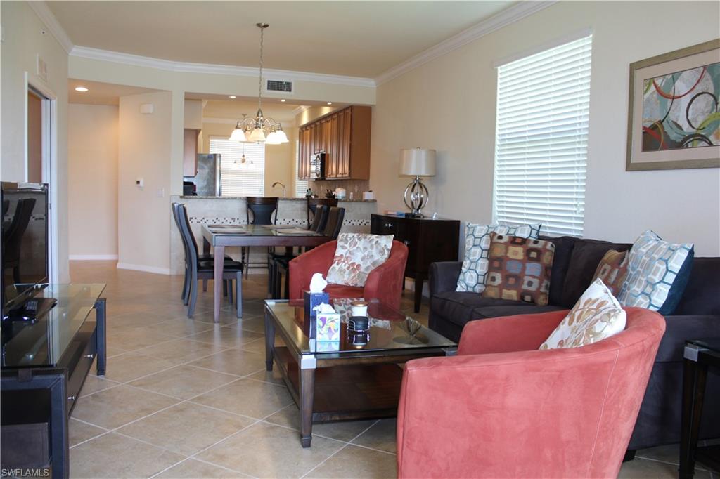 9735 Acqua Court, Unit 611 Naples, FL 34113 - Photo 9 of 30 Living area featuring crown molding, light tile patterned flooring, and a chandelier