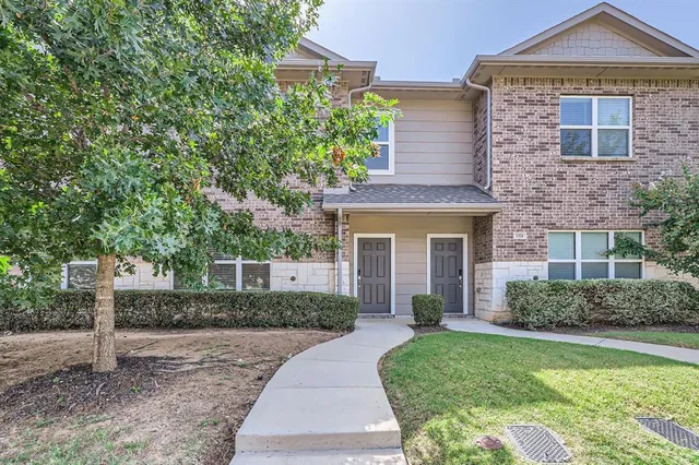 a front view of a house with a yard and potted plants