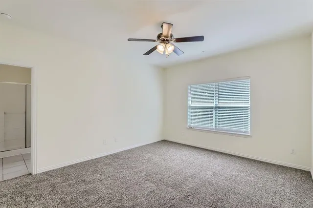 an empty room with a window and a fan