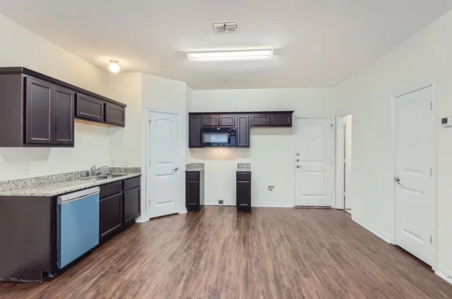 a kitchen with stainless steel appliances granite countertop wooden cabinets and wooden floor